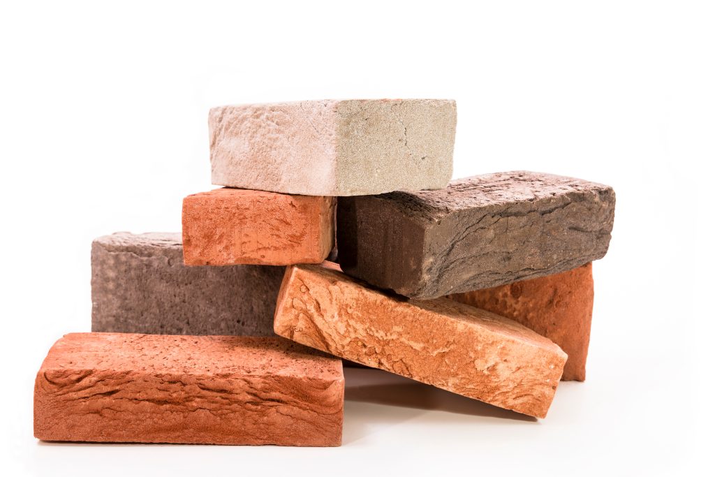 A pile of red, brown, and tan bricks that's used to explain the importance of choosing the right materials for a fireplace renovation.