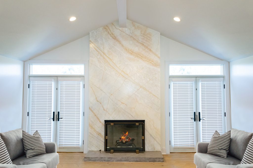 Contemporary living room with a modern fireplace featuring a sleek marble wall and minimalist glass enclosure.