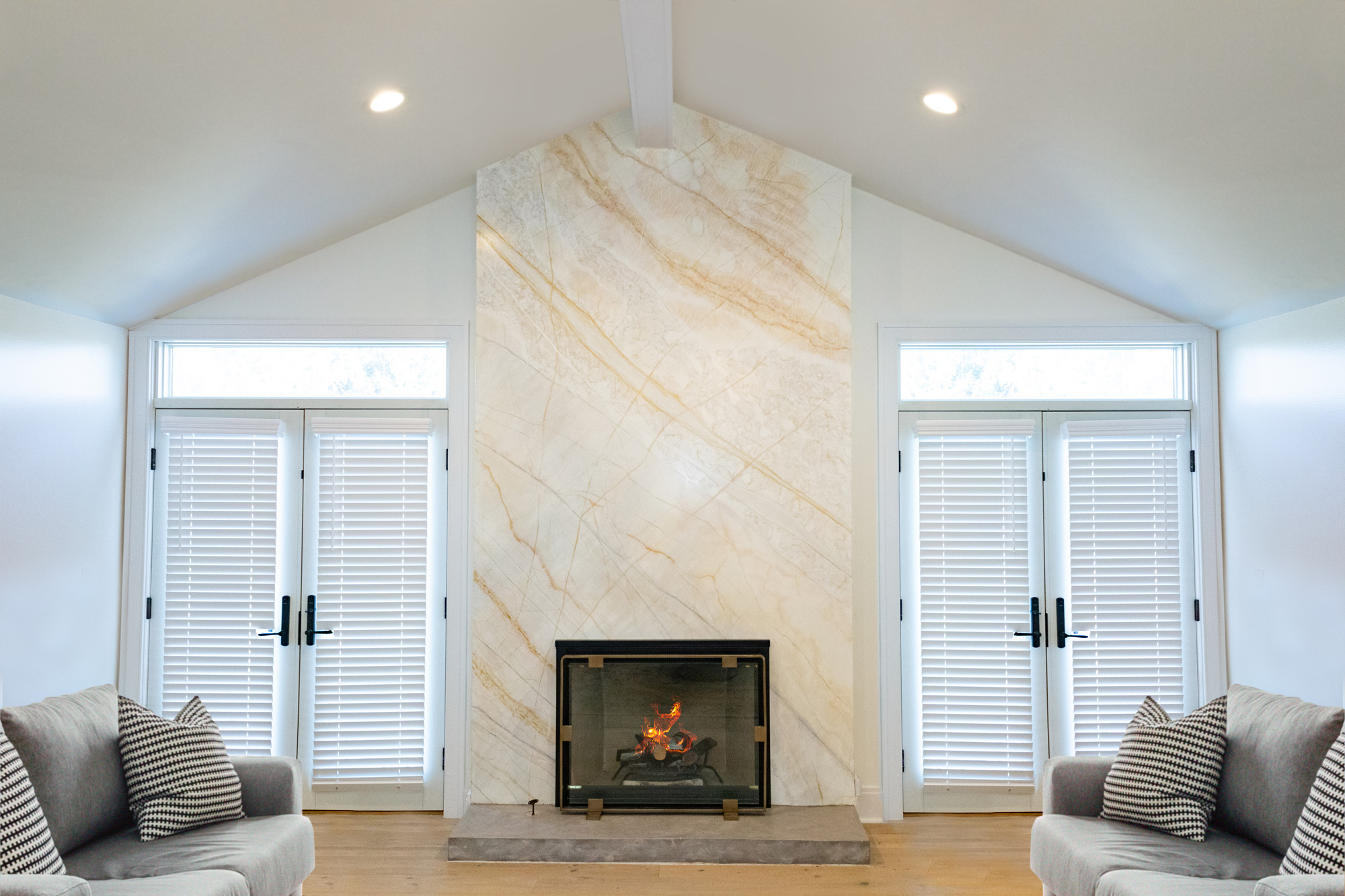 Contemporary living room with a modern fireplace featuring a sleek marble wall and minimalist glass enclosure.